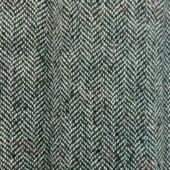 Herringbone tweed fabric, dark green and off-white, repeating V-pattern with orange and brown flecks, dense nubby weave, muted earthy tones.