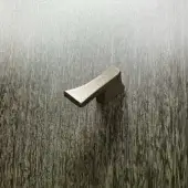 Bronze handle, geometric form, brushed finish, rests on dark brown wood grain surface with linear texture, soft diffused lighting.