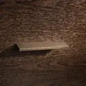 Brass cabinet pull with “BELLAVISTA” etching on dark, textured wood displaying a prominent grain and knots, warm golden tones.