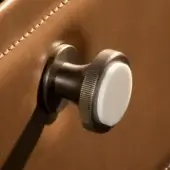 Antique bronze knobs with buffalo bone inserts mounted on brown leather, featuring ribbed cylindrical bases and circular caps.