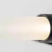 Cylindrical wall light, matte black metal housing, frosted glass tube emitting warm light, minimalist modern design, diffused glow, shadow detail.