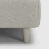 Sofa leg detail, light gray herringbone fabric upholstery, tapered light beige painted wood leg with rounded top and flared base, product label visible.