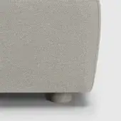 Sofa side detail, beige herringbone fabric upholstery, cylindrical vasetto leg, rounded edge, boxy form, neutral white background.