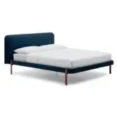Teal velvet bed with rectangular headboard, low profile frame, and burgundy-red metal legs, styled with white linen bedding in studio lighting.