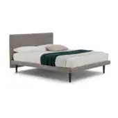 Bed base upholstered in light brown textured fabric, rectangular headboard, white linens, teal throw, tapered dark legs, minimalist design.