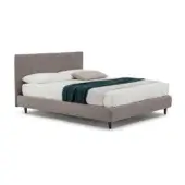 Upholstered bed with light brown headboard, platform base, white linens, and teal throw; dark gray tapered legs support frame.