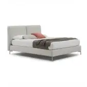 Bed base, light gray upholstery, rectangular headboard with vertical seam, brushed silver legs, white linen duvet, rust velvet pillow.