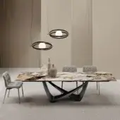 Extendable table, marble-look top, black metal base, with gray dining chairs and spherical pendant lights, neutral studio setting.