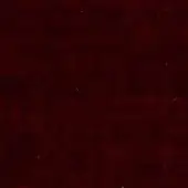 Red velvet fabric with a short, dense pile and mottled texture, displaying a rich crimson and burgundy color palette under even lighting.