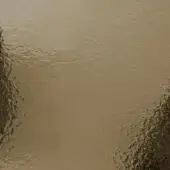 Hammered bronze glass texture displays mottled surface with indentations, warm muted bronze tones, and subtle reflective highlights under diffused lighting.