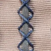 Beige ribbed textile with dark blue vertical stitching in interconnected X shapes, handwritten text visible at top edge.
