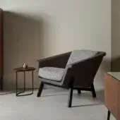 Distinguished Horm Sienna lounge chair with enveloping form upholstered in brown material and light grey textile cushions with dark wood legs