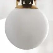 Blown glass globe light fixture, satin white finish, with brass conical cap and mounting bracket, studio lighting.