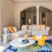 Distinguished Frag Hug sectional with welcoming volumes and curved armrests upholstered in light beige textile with orange pillows