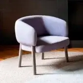Sophisticated Bross Aretha lounge chair with curved form and light lavender textile upholstery supported by light-toned wood legs