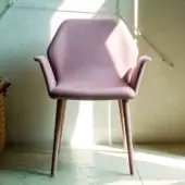 Bross Ava armchair, dusty rose fabric, curved high-back design with tapered light pink legs, positioned on tiled floor in sunlight.