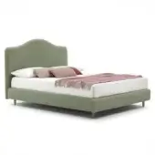 Green velvet bed frame with curved headboard and tapered legs, styled with white bedding and terracotta-rose accent pillows.