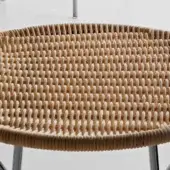 Round wicker table with light tan woven top and chrome metal base, featuring a raised circular border and grid pattern.