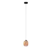 Amber glass pendant light with rounded oblong shade, black canopy, and thin dark wire suspension in a minimalist studio setting.