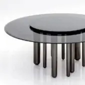 Round coffee table, fumé glass top, concentric circle detail, black nickel legs of varying heights, modern design, reflective white background.