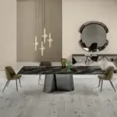 Extendable dining table, dark marble top, conical dark gray base, with four olive green chairs, frosted glass chandelier, beige ribbed wall.