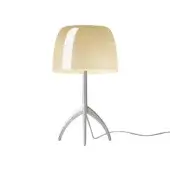 Foscarini Lumiere Grande table lamp, warm white aluminum, with translucent pale yellow curved lampshade and tripod base.