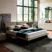 Distinguished Cattelan Italia Adam bed with gently curved padded headboard and dark Canaletto walnut legs upholstered in light beige synthetic leather