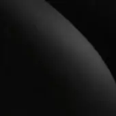 Dark sphere against black background, smooth gradient from gray to black, subtle tonal shifts, matte finish, scattered light specks.