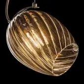 Pendant light, amber ribbed glass, oval shade with brushed brass arm and circular mounting plate, illuminated, translucent design.