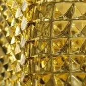 Yellow carved crystal texture, “alba,” displays repeating triangular and rectangular facets, creating a glossy, reflective, geometric pattern.