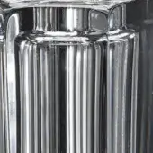 Transparent glass cylinder, hand-carved with vertical ribbed texture, polished finish, smooth curves, sleek design, dark background.