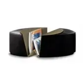 Black leather ottoman with brass angular cutouts displaying magazines, studio shot, flattened cylinder shape, modern geometric design.