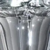 Clear glass decorative object, vertical ridges, molded geometric floral patterns, glossy reflective surface, bright directional lighting.