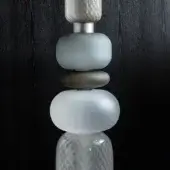 Glass sculpture, speckled gray, sage green, brown, white, clear glass, silver metal bands, dark textured wall background.