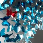 Blue butterfly mobile with reflective surfaces, layered composition, and a central red butterfly suspended on thin wires against a gray background.