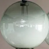 Blown glass pendant light, milky green, spherical shape suspended by metallic rods from a circular ceiling mount, diffused illumination.