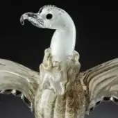 Glass condor sculpture, clear with gold and beige swirls, featuring outstretched wings and detailed head, displayed against a dark gray backdrop.