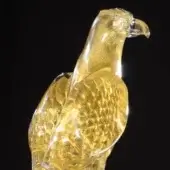 Glass falcon sculpture, amber translucent glass, gold flecks, poised stance, detailed feathering, streamlined form, labeled “gold – falcon”.