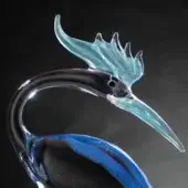 Glass bird sculpture, clear with blue accents, features a slender neck, marbled black body, and translucent crest against a dark gray backdrop.