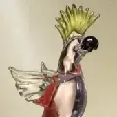 Glass parrot sculpture, transparent with red & green accents, dynamic wings-up pose against a beige backdrop.