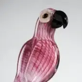 Glass parrot sculpture, pink and red, detailed feathered texture, black beak, translucent body, three-quarter profile, light gray background.