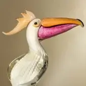 Glass pelican sculpture, clear and white, with textured body, orange beak, amber crest, displayed against a beige backdrop.
