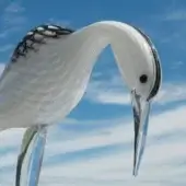 Glass flamingo sculpture, clear and black, stylized with elongated neck and bowed head against a blue sky backdrop.