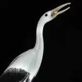 Glass stork sculpture, transparent with brown base, long neck and detailed amber beak, studio lighting, black background.