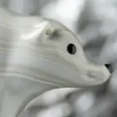 White bear sculpture, agate-like material, stylized head and neck profile with dark eyes and nose, layered patterns, smooth contours.