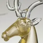 Glass deer sculpture, amber head and clear body, detailed antlers branching symmetrically, glossy finish, neutral gray background.