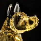 Glass dog sculpture, amber and black, featuring swirling translucent patterns and elongated ears in a dynamic, stylized form.