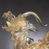 Glass dragon sculpture, transparent with gold inclusions, dynamic pose featuring outstretched claw and partially unfurled wings.