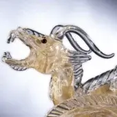Glass dragon sculpture with gold flecks, amber tone, detailed scales, open mouth, black eye, swirling dark glass accents, dynamic serpentine form.