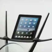 Exercise bike handlebar in black metal with integrated iPad tablet holder displaying app icons against a cloudy sky background.
